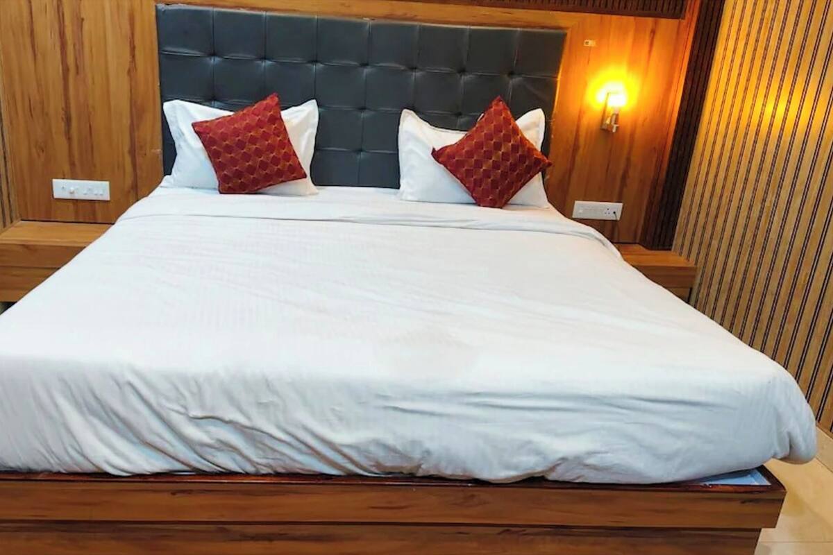 Una cama grande con cabecera de madera y dos mesitas de noche, cada una con una lámpara.