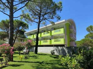 Ein modernes Gebäude mit Grün-Weiß-Farbgebung, umgeben von üppiger Vegetation und Bäumen.