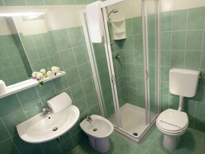 A bathroom with a shower, sink, bidet, toilet, and a mirror. - Holiday apartment with air conditioning and balcony (Bibione)