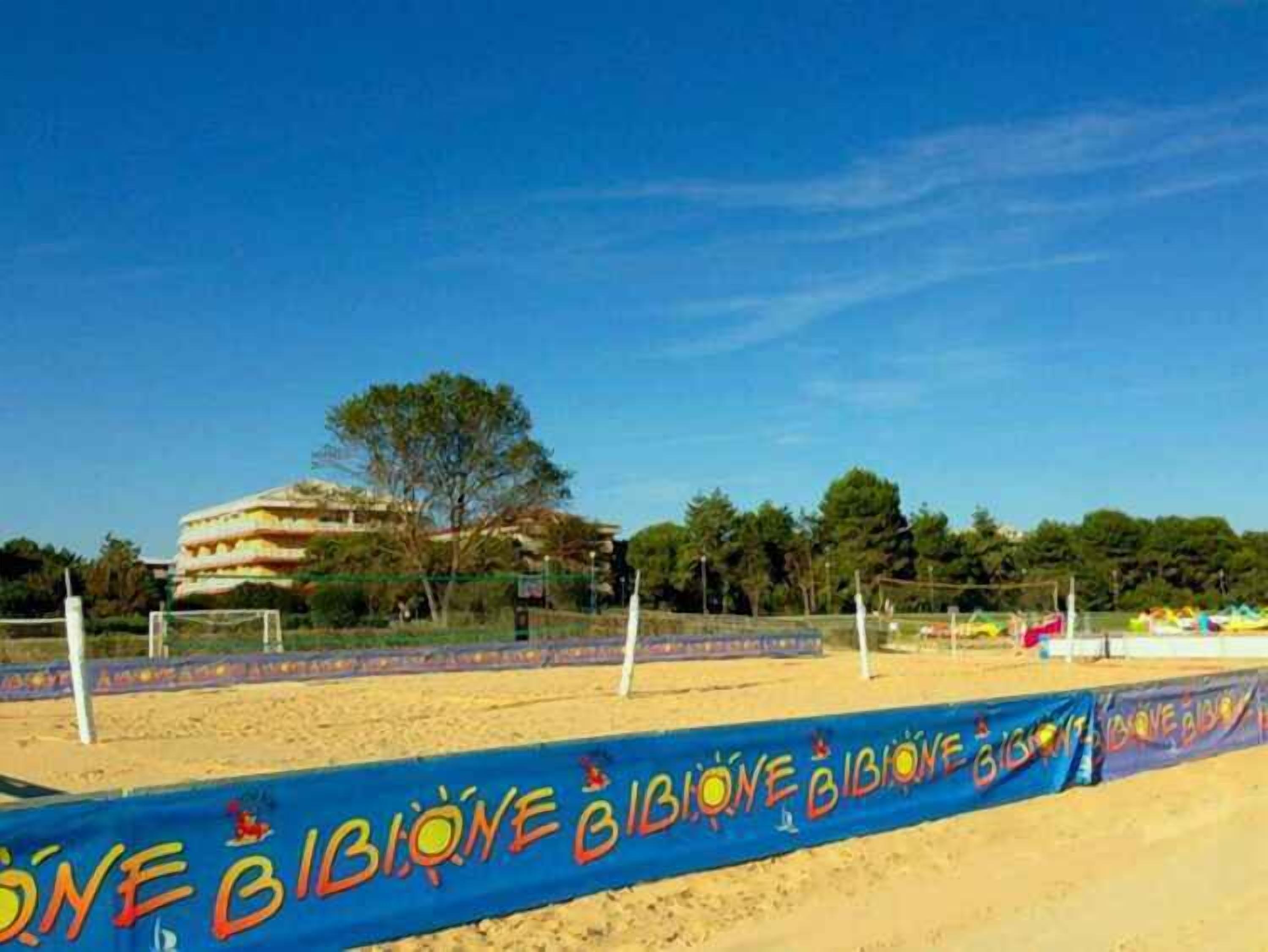 A beach volleyball court with a blue banner reading "BIBIONE BIBIONE".