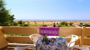 Een balkon met een tafel voor twee personen, met uitzicht op een strand.