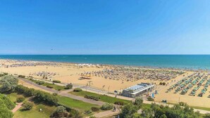 A beach with numerous umbrellas and sun loungers, a clear sky, and a calm sea. - Studio with air conditioning, balcony and pool (Bibione)