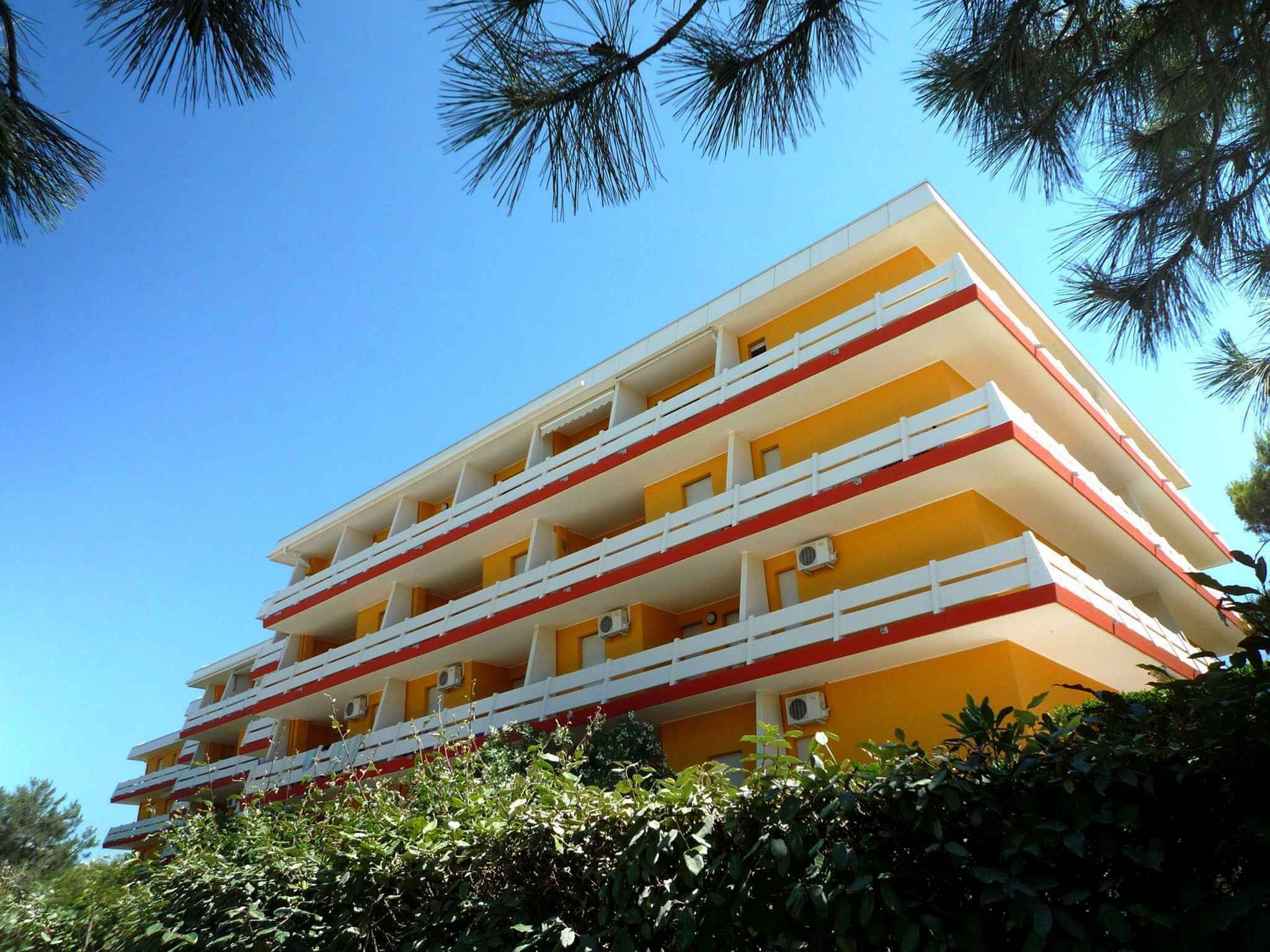 Un immeuble à plusieurs étages, doté de balcons et entouré de verdure.
