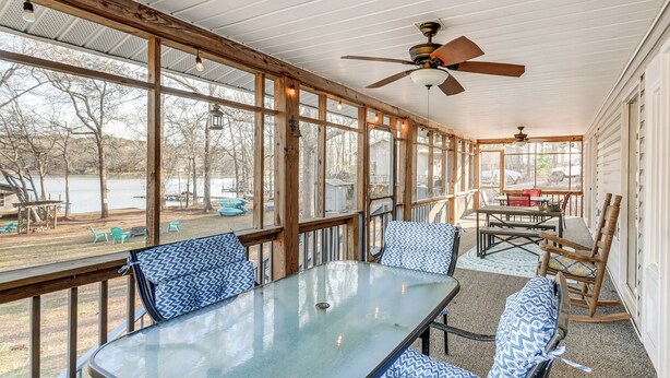 A covered patio with a table and chairs, large windows, and a ceiling fan. - Fish & Swim Off the Dock: Lake Sinclair Family Gem (Eatonton)