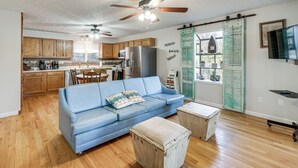 A spacious living area with a blue sofa, wooden cabinets, and a kitchen in the background. - Fish & Swim Off the Dock: Lake Sinclair Family Gem (Eatonton)