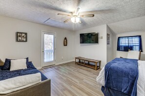 A bedroom with a bed, a sofa, a ceiling fan, and a wooden bench.