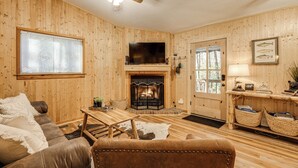Ein gemütliches Holzhaus-Interieur mit Kamin, Ledermöbeln und einem Fernseher.