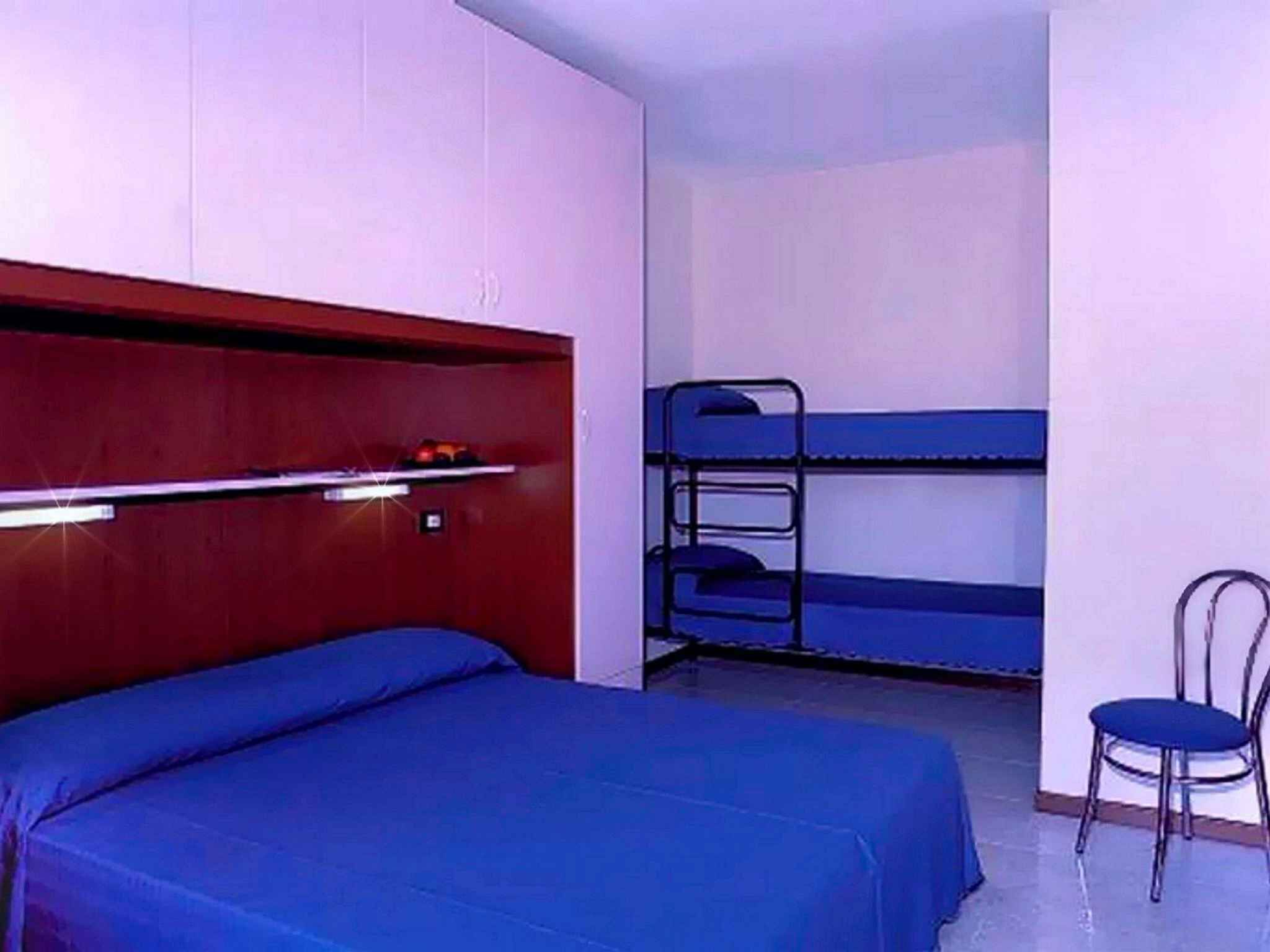 A small room with a bunk bed, a desk, and a chair.
