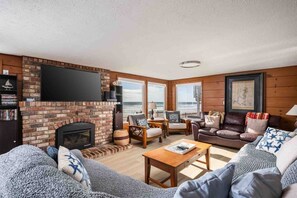 Ein Wohnzimmer mit Kamin, Fernseher und Meerblick.