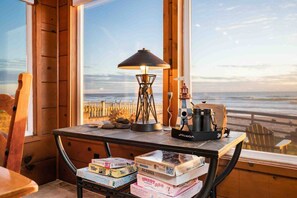 Ein Holztisch mit Lampe, Büchern und Fernglas an einem Fenster mit Blick auf den Ozean.
