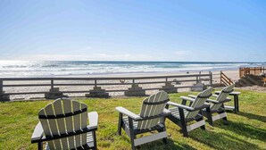 Uitzicht op het strand met stoelen en een houten hek.