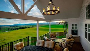A covered outdoor seating area with a view of a green field and mountains. - The Quandary Vineyards Estate (Yamhill)