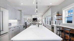 A spacious kitchen with a large island, white cabinetry, and a view of the outdoors through large windows. - The Quandary Vineyards Estate (Yamhill)
