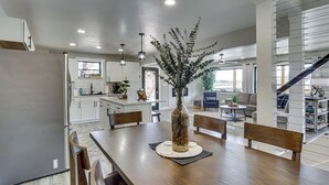 A modern kitchen with white cabinets, a dining table with chairs, a vase with dried plants, and a staircase leading to another level. - Private Dock & Theater Room: Lake Ozark Luxury (Lake Ozark)