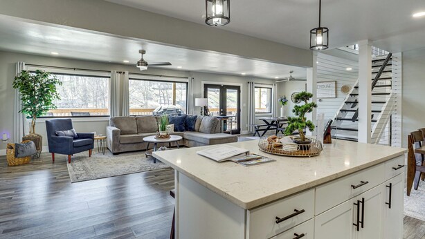 A spacious living area with a large island, a staircase, and a view of the outdoors. - Private Dock & Theater Room: Lake Ozark Luxury (Lake Ozark)
