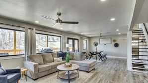 A spacious living room with a sectional sofa, a round coffee table, and a ceiling fan. - Private Dock & Theater Room: Lake Ozark Luxury (Lake Ozark)