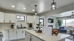 A modern kitchen with white cabinets, a marble countertop, and pendant lighting. - Private Dock & Theater Room: Lake Ozark Luxury (Lake Ozark)