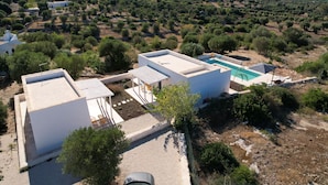 Une villa moderne dotée d’une piscine, entourée d’oliveraies et située dans un paysage vallonné.