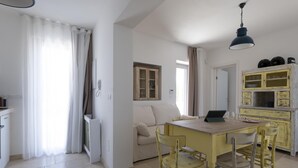 Un salon lumineux avec une table jaune et un canapé blanc, une cuisine avec des meubles jaunes et un coin repas avec une table et des chaises.