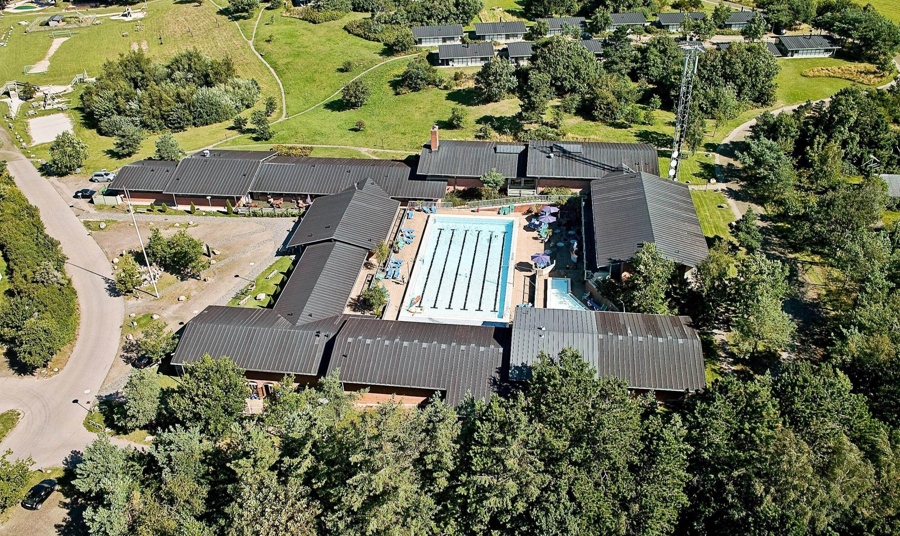 Vue aérienne d’un quartier résidentiel comprenant plusieurs maisons, une piscine et un court de tennis.