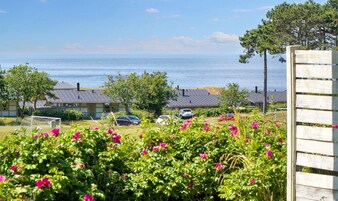 Una zona residencial costera con casas, vista al mar y un cerco de madera.