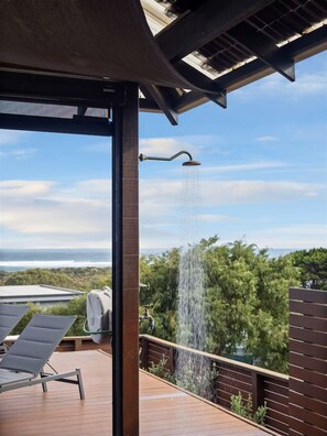 A covered outdoor area with a built-in shower, a wooden deck, and a view of the ocean. - Baudin Beach House - stunning ocean views & coastal charm with resort-style pool (Gnarabup)