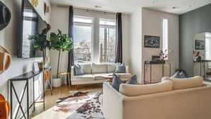 Una sala de estar moderna con un sofá, una mesa de centro, un televisor y un ventanal con cortinas.