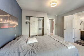 A bedroom with a large bed, a walk-in closet, and a door leading to another room. - Hike, Bike & Ski! Cozy Anchorage Townhome (Anchorage)