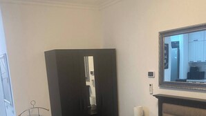 Ein Hotelzimmer mit einem Bett, einem Schrank, einem Spiegel und einem kleinen Tisch mit einer Lampe.