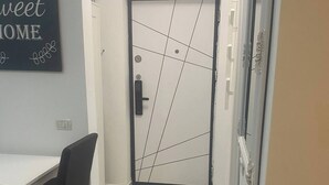 Ein modernes Interieur mit einem weißen Schreibtisch, einem schwarzen Stuhl und einer Tür mit geometrischem Muster.