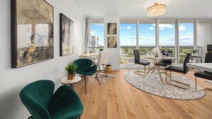 A spacious living area with a dining set, green chairs, and artwork on the walls. - Elegant Condo w/ Stunning Views in Dtwn Hollywood (Hollywood)