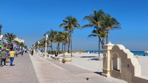 A beach promenade with palm trees, a clear sky, and a sandy beach. - Elegant Condo w/ Stunning Views in Dtwn Hollywood (Hollywood)