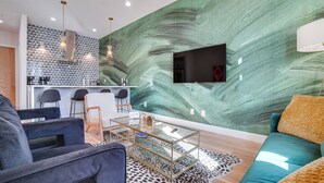 A modern living room with a glass coffee table, a teal sofa, and a leopard print rug. - 1 Mi to Nashville General: Upscale Townhome (Nashville)