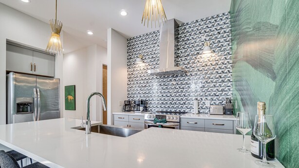 A modern kitchen with a large island, stainless steel appliances, and patterned backsplash. - 1 Mi to Nashville General: Upscale Townhome (Nashville)