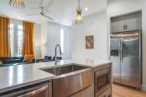 Eine moderne Küche mit einem Edelstahl-Kühlschrank, einem eingebauten Backofen und einer großen Kochinsel mit Spüle.