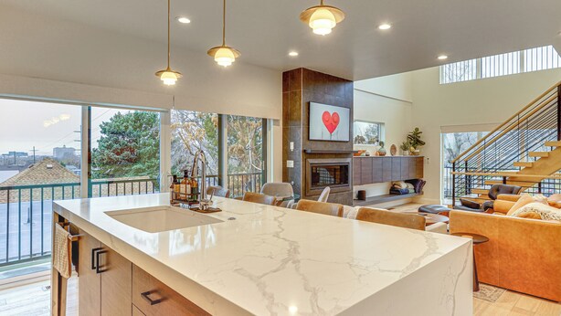 Una cocina amplia con una isla grande, modernas lámparas colgantes y vistas al exterior.