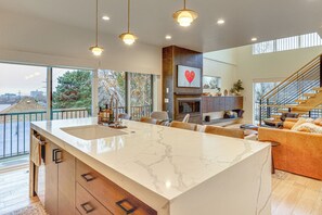 Una cocina amplia con una isla grande, modernas lámparas colgantes y vistas al exterior.