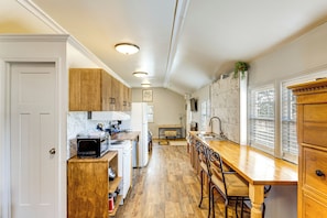 Una cocina con armarios de madera, salpicadero de mármol y una mesa de comedor de madera con taburetes tipo barra.