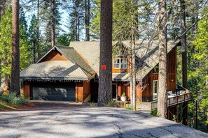 Eine Hütte mit Garage, Terrasse und einem großen Baum davor.