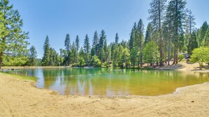 A sandy beach with a calm lake surrounded by tall pine trees. - Game Room & Hot Tub! Dog-Friendly Arnold Retreat (Arnold)
