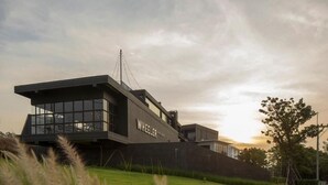 Un bâtiment moderne, facilement reconnaissable grâce à une grande enseigne « WHEELER », doté d’une vaste façade vitrée et d’une toiture inclinée.
