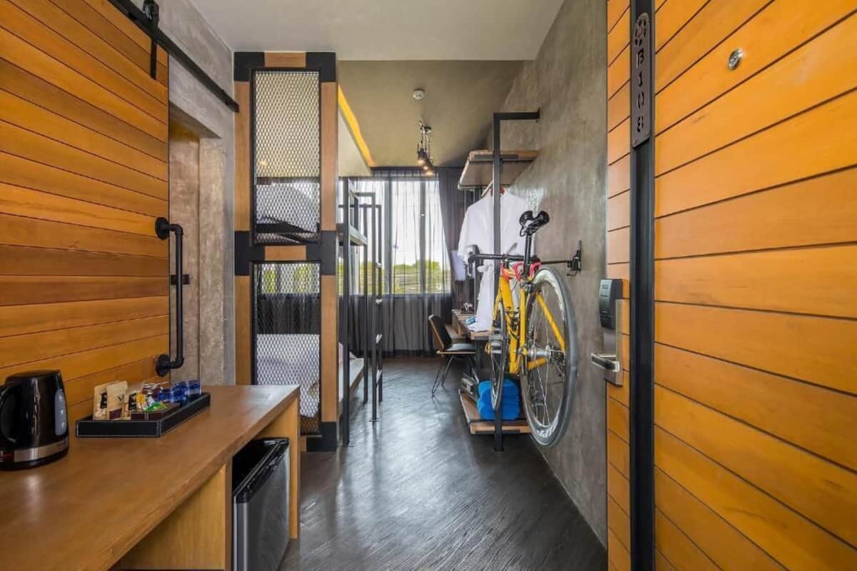 Un pasillo estrecho con paredes de madera, una bicicleta, una cafetera y un pequeño rincón con asientos.