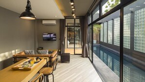 Un salon moderne avec un coin repas, de grandes fenêtres et un téléviseur.