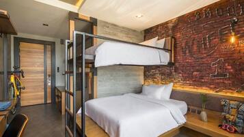 A modern hotel room with a bunk bed, a wooden desk, and a brick wall with graffiti.