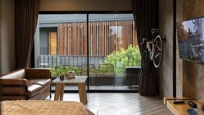 Une chambre d’hôtel moderne avec un grand lit, un canapé, une petite table et un téléviseur.