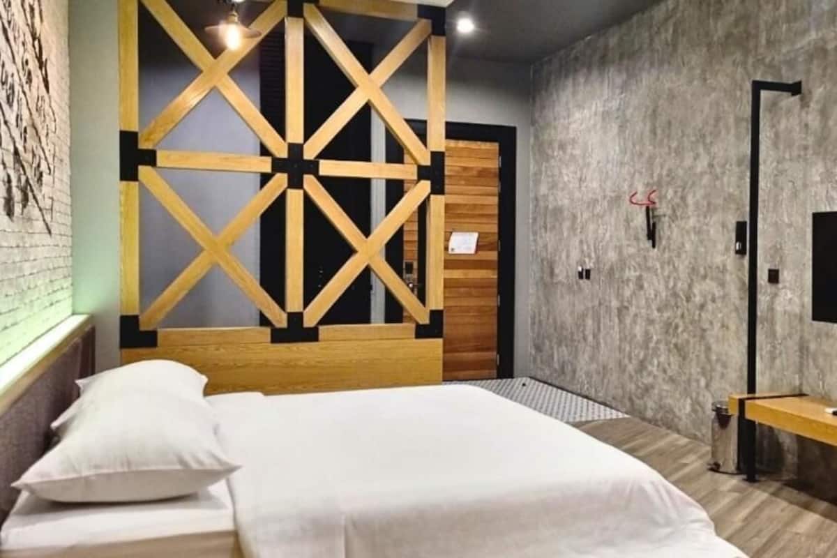 Un dormitorio moderno con una cama grande, cabecera de madera, televisor montado en la pared y una mesita de noche pequeña.