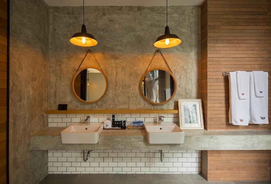 A bathroom with two sinks, two round mirrors, and two pendant lights.