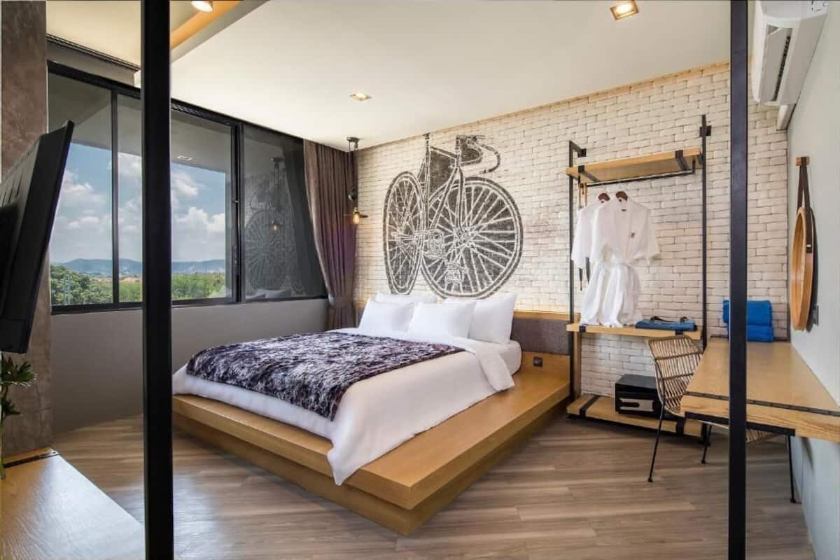 Un dormitorio moderno con una cama grande, un mural de bicicleta, un perchero colgante y vistas al exterior.