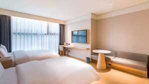 A modern hotel room with two large beds, a small desk, a round table, and a TV mounted on the wall. - Vienna Classic Hotel (Beijing)