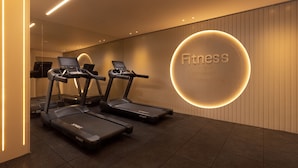 A fitness center with treadmills, a wall-mounted circular sign, and a mirrored wall. - Light Filled Modern Eilat Getaway (Eilat)